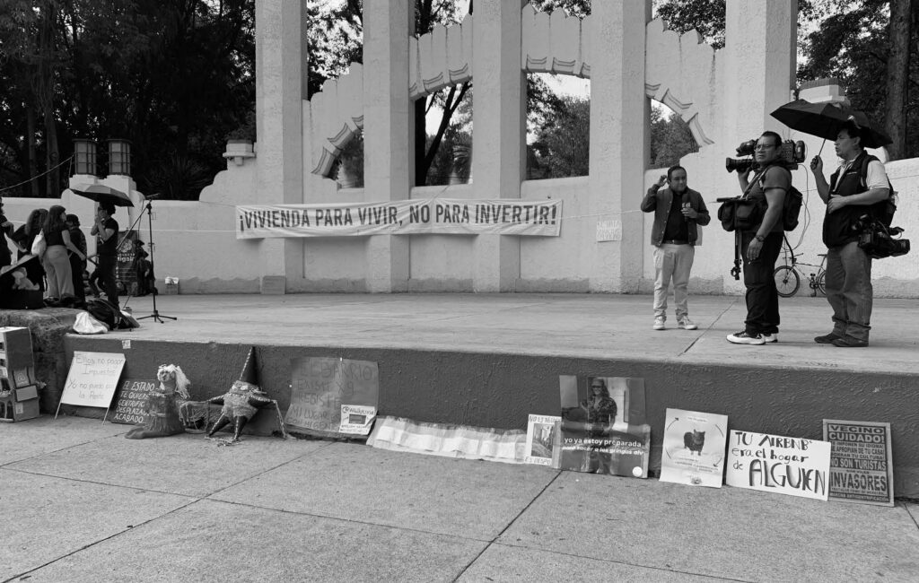 Manifestación contra la gentrificación en la Ciudad de México con una manta que dice “Vivienda para vivir, no para invertir” y presencia de medios de comunicación.